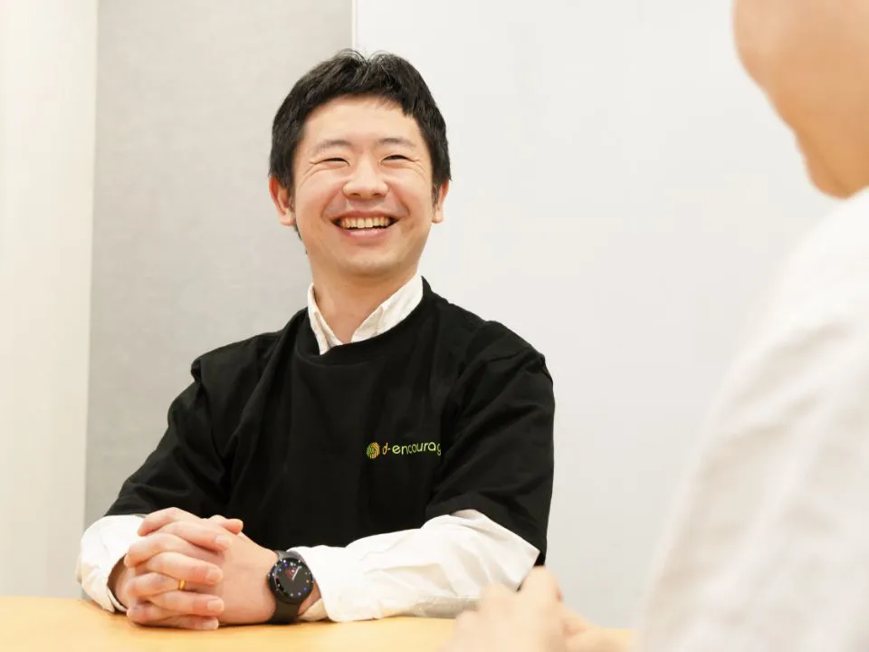 K.Y.さん仕事風景。テーブルでご利用者さまと向かい合い、面談を行う様子。