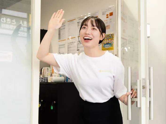 施設の入口でドアを開け、来所者に挨拶している様子。