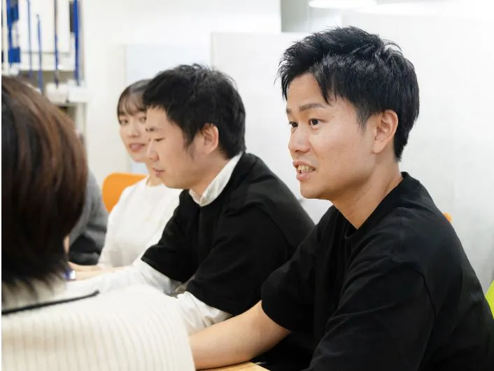 テーブルを囲んで朝礼をしている様子。