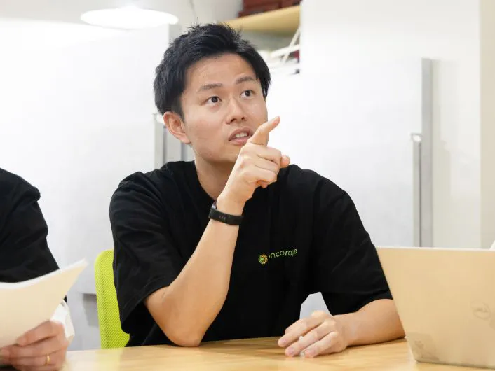 サービス管理責任者の仕事風景。テーブルで資料とノートパソコンを使い、打ち合わせをしている様子。