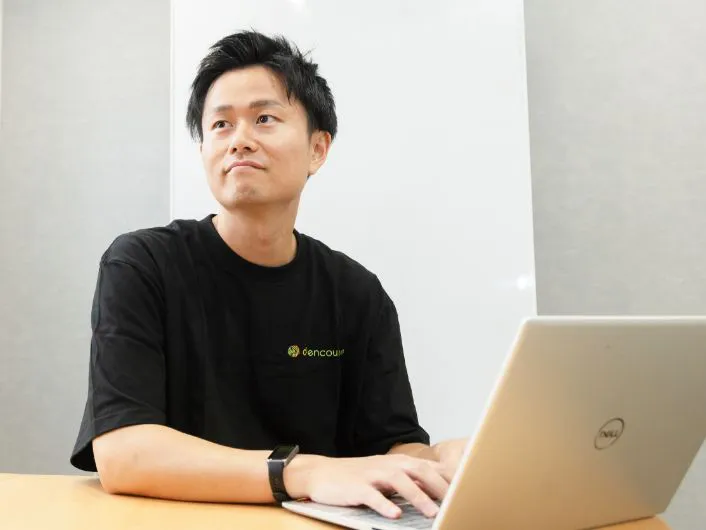 サービス管理責任者の仕事風景3。テーブルでノートパソコンを使って作業している様子。