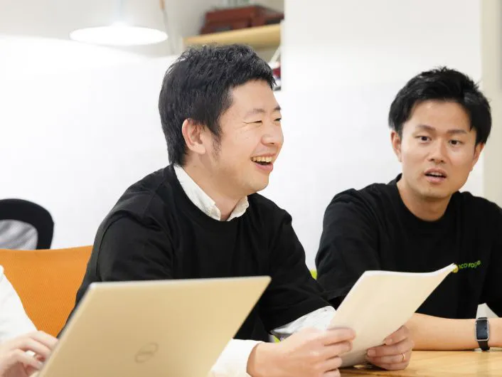 施設管理者の仕事風景1。テーブルを囲んで資料を持ちながら打ち合わせをしている様子。