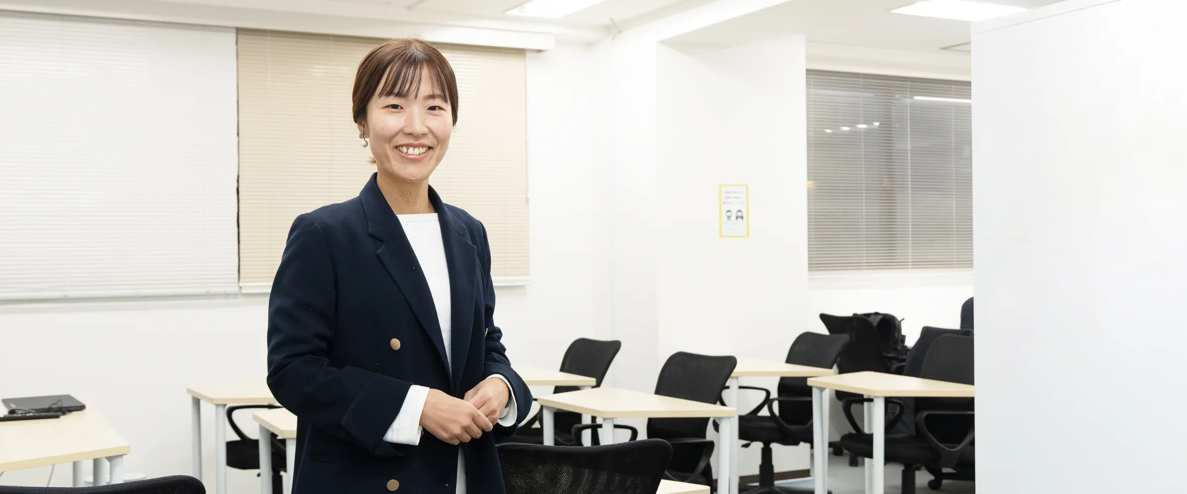 M.M.さんインタビューのキービジュアル。訓練スペースを背景に笑顔で立っている様子