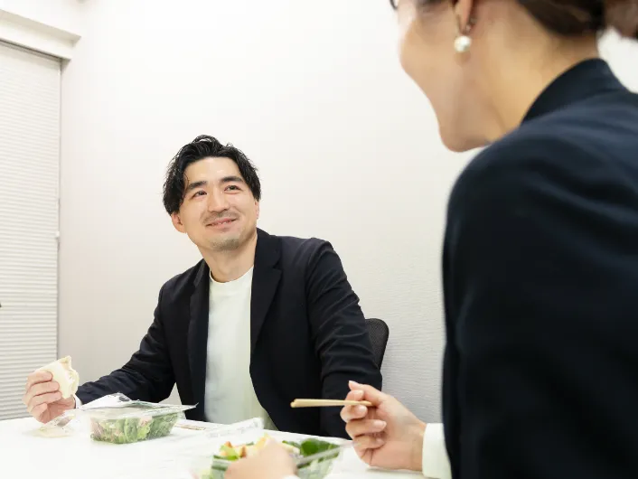同僚とランチを食べながら談笑する様子
