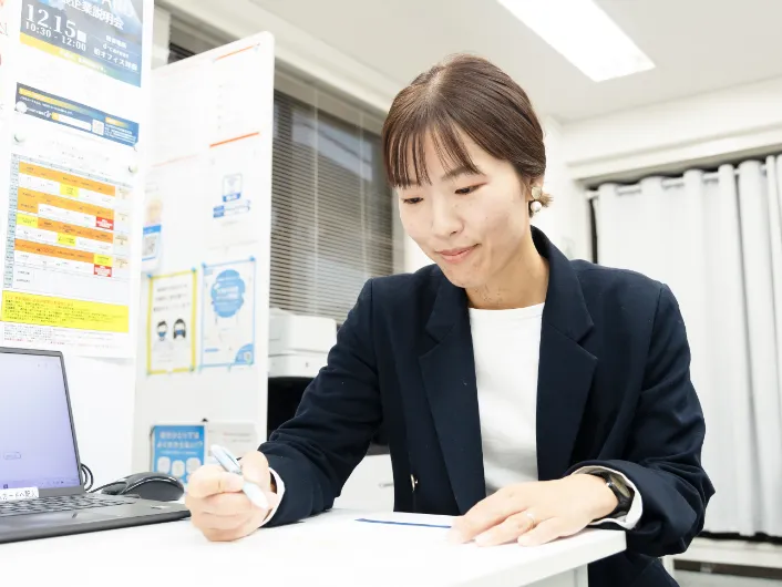 スタッフ終礼後に支援日誌を作成する職業指導員、デスクでペンを持ち記入している様子